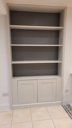 an empty bookcase in the corner of a room with tile flooring and white walls