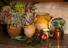 an assortment of kitchen utensils and flowers in vases on a counter top