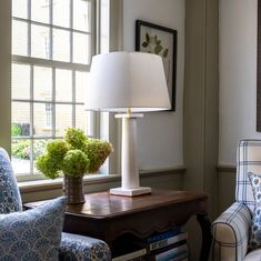 a lamp sitting on top of a wooden table next to a blue and white chair