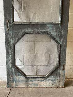 an old door is painted green and has two octagonal glass panels on the front side