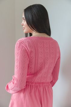 This hot pink knit cardigan features a charming pointelle heart design and button closure, adding a touch of whimsy to any outfit. Its cropped fit and scalloped hem give it a unique look, while the V-neckline and long sleeves provide comfort and versatility. Perfect for layering or adding a pop of color to any wardrobe. hot pink pointelle hearts cropped fit scalloped hem button front v-neckline long sleeves model is wearing a small Feminine Long Sleeve Sweater In Pointelle Knit, Feminine Long Sleeve Pointelle Knit Sweater, Pink Cropped Cardigan For Spring, Chic Cropped Pink Cardigan, Fitted Cropped Pointelle Knit Cardigan, Pink Textured Knit Cropped Sweater, Fitted Pointelle Knit Cropped Cardigan, Pink Pointelle Knit Cardigan, Feminine Pink Pointelle Knit Sweater