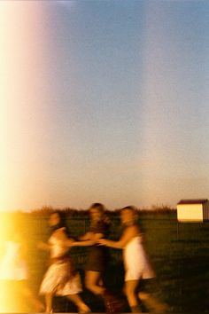 a group of people standing next to each other on a field with a kite flying in the sky