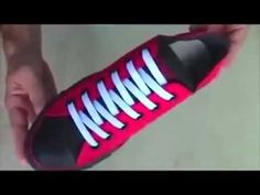 someone is holding a red and black shoe with white laces on the soles