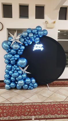 a large balloon arch with blue balloons and stars on it in front of a door