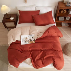 a bed with an orange comforter and pillows