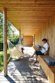 two people sitting in hammocks on a wooden porch next to a grassy area