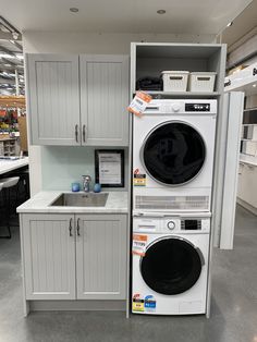 a washer and dryer stacked on top of each other in a room with white cabinets