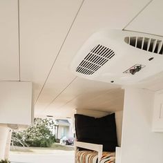 an air conditioner mounted to the side of a wall next to a chair and table