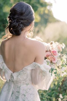 the back of a woman's dress with flowers in her hair, holding a bouquet