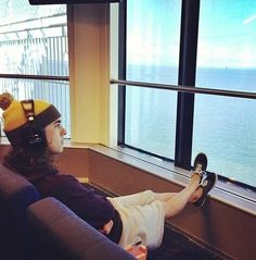 a person sitting on a couch with their feet up against the window sill and wearing a beanie