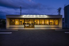 an empty parking lot in front of a store with lights on and windows lit up