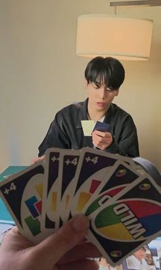 a person sitting at a table with four cards in front of them and one holding a cell phone