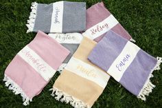 four personalized towels laying on the grass with name written on one side and another towel in the other