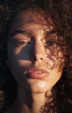 a woman with long curly hair looking at the camera