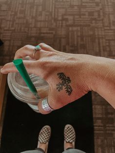 a person's hand with a small tattoo on it holding a drink in their left hand