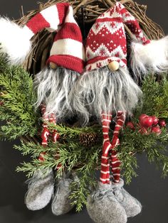 two knitted gnomes sitting on top of a wreath