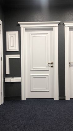 two white doors are open in a room with black walls and blue carpeted flooring