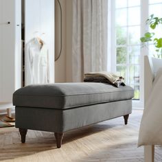 a grey ottoman sitting on top of a hard wood floor