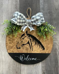 a welcome sign with a horse on it and some plants hanging from the front door