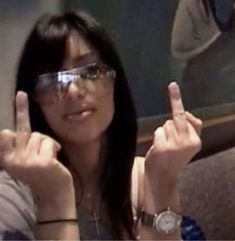 a woman wearing glasses making the middle finger sign