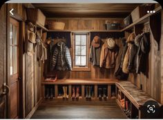 the inside of a wooden closet with many coats and boots