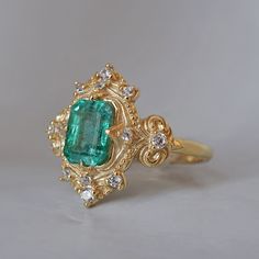 Read about our payment plans before proceeding. Palais d'Émeraude: A Parisian Royal Masterpiece Introducing the Emerald Palais Diamond Ring, an exquisite ring that captures Parisian elegance and sophistication. At its center, a lush emerald evokes the opulence of royal gardens. Inspired by Parisian palaces, this ring features delicate curves and ornate details that wrap around the vibrant emerald. The meticulous craftsmanship makes it a true masterpiece, fit for royalty. "Palais" translates to "Palace," reflecting the regal beauty and timeless charm of this piece. The emerald symbolizes rebirth, love, and fortune, elegantly embraced by the intricate band. All orders come in our Tippy Taste ring box. This ring is handmade and designed in NYC. 14K or 18K solid gold Natural emerald-cut emeral Regal Rings, Parisian Elegance, Royal Garden, Fancy Rings, Jewelry Lookbook, Jewelry Inspo, Natural Emerald, Ring Box, Emerald Cut