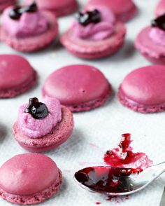 pink macaroons with blueberries on them and a spoon full of icing