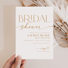 a woman holding up a card with the words bridal shower written in gold on it