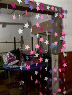 pink and purple stars hanging from the ceiling above a blue table in an empty room