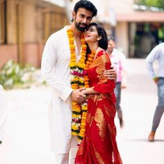 a man and woman standing next to each other in front of a building with flowers on it