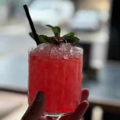 a person holding up a drink with a straw in it's glass and garnish on the rim