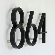 a black metal number is mounted on a white wall