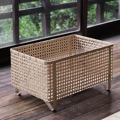 a wicker basket sitting on top of a wooden floor next to a large window