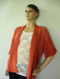 a mannequin wearing an orange knitted cardigan over a white lace top