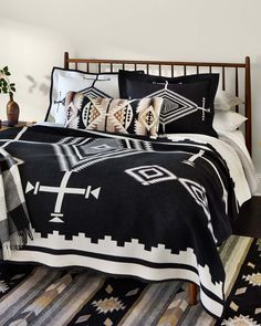 a black and white bed in a bedroom next to a plant on a table with two vases