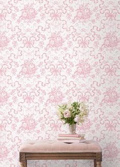 a vase with flowers sitting on top of a wooden bench next to a wall paper