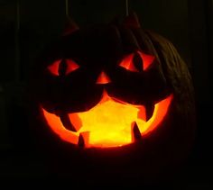 a carved pumpkin with two faces on it's face, lit up in the dark