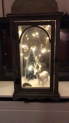 a snowman and reindeer in a glass case with lights on it's sides