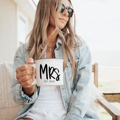 a woman sitting on a bench holding a coffee mug with the word mr and mrs printed on it