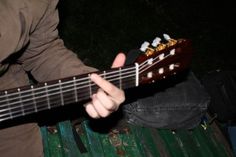 a person holding a guitar in their right hand and playing it on the other side