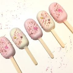 five pink and white cake pops with sprinkles on them are lined up in a row