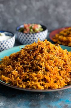 a plate full of rice and other food items on a table with bowls in the background