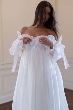 a woman wearing a white dress with ruffled sleeves