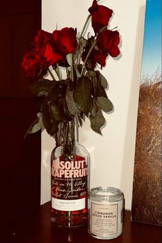 a vase filled with red roses next to a candle