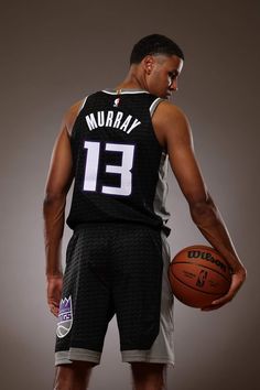 a man holding a basketball in his right hand and wearing a jersey with the number 13 on it