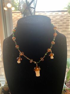 a handmade choker made with glass mushroom charms, orange rondelle beads, and green seed beads. Mushroom Necklace Bead, Mushroom Necklace Beads, Diy Pendants, Pride Necklace, Mushroom Necklace, Handmade Chokers, Glass Mushrooms, Necklace Beads, Handmade Beaded Necklaces