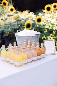 bottles of liquid are lined up on a table with sunflowers in the background