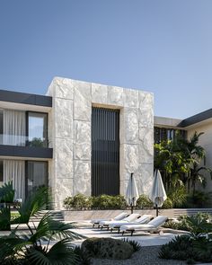 an outdoor pool with lounge chairs and umbrellas in front of a modern building that looks like it is made out of stone