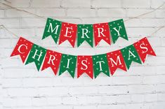 merry christmas banner hanging on brick wall with red and green banners in front of it