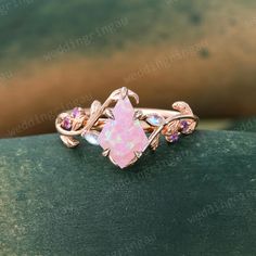 a pink opalite ring on top of a green velvet covered surface with leaves